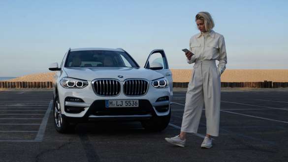 App My BMW Modèle féminin BMW avec smartphone devant BMW App My BMW Modèle féminin BMW avec smartphone devant BMW