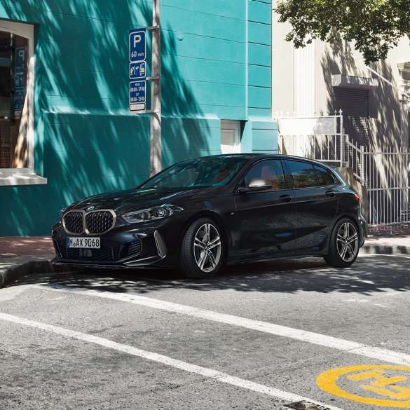 BMW M135i xDrive, vue de trois quarts de profil. BMW M135i xDrive en Saphirschwarz metallic, vue de trois quarts de profil, en stationnement.