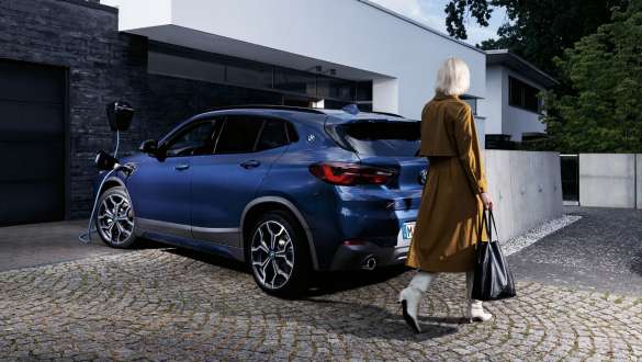 Plug-in Hybrid BMW X2 xDrive25e F39 vue de trois quarts arrière en charge Plug-in-Hybrid BMW X2 xDrive25e F39 vue de trois quarts arrière en charge avec mannequin