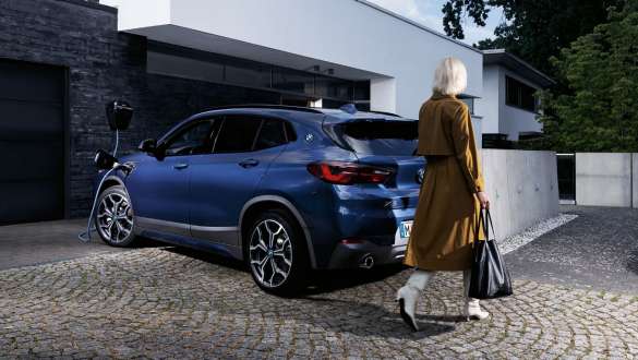 Plug-in Hybrid BMW X2 xDrive25e F39 vue de trois quarts arrière en charge Plug-in-Hybrid BMW X2 xDrive25e F39 vue de trois quarts arrière en charge avec mannequin