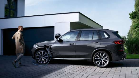 Plug-in Hybrid BMW X5 xDrive45e G05 vue de profil devant garage Plug-in Hybrid BMW X5 xDrive45e G05 vue de profil devant garage avec modèle