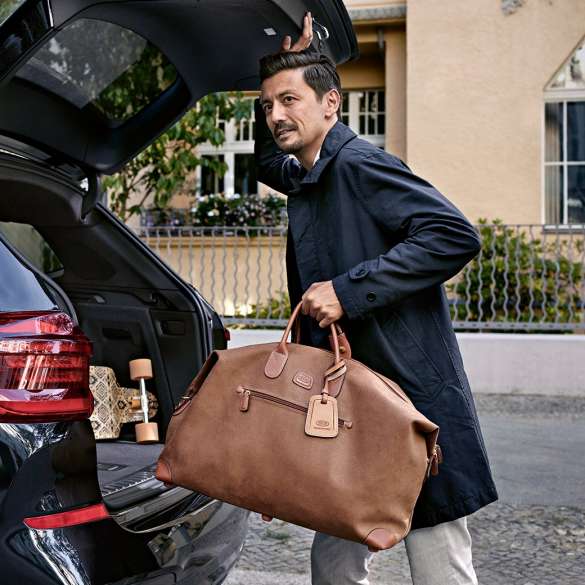 Service Après-vente entreprises BMW, Service haut de gamme Service haut de gamme : Un homme range un sac dans le coffre à bagages d’une BMW