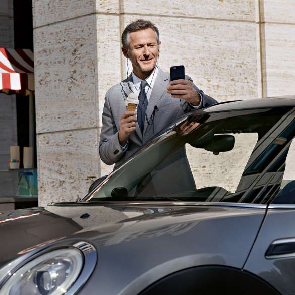 Service Après-vente entreprises BMW, contrôle de l’état des finances Service Après-vente entreprises BMW : Un homme mange une glace tout en contrôlant l’état de ses finances sur son smartphone