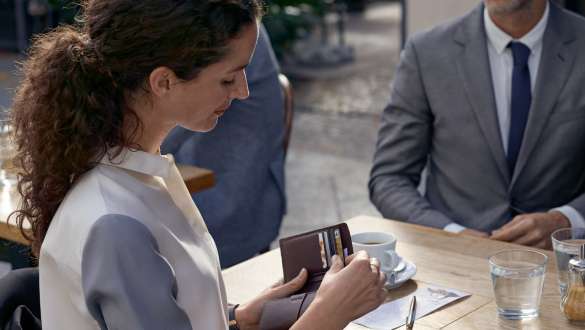 Maintenance préventive BMW Maintenance préventive : Une femme est assise à une table avec un porte-monnaie dans la main