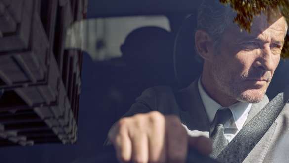 Service intégré BMW Service intégré BMW : Un homme est assis au volant d’une BMW et regarde dans le rétroviseur