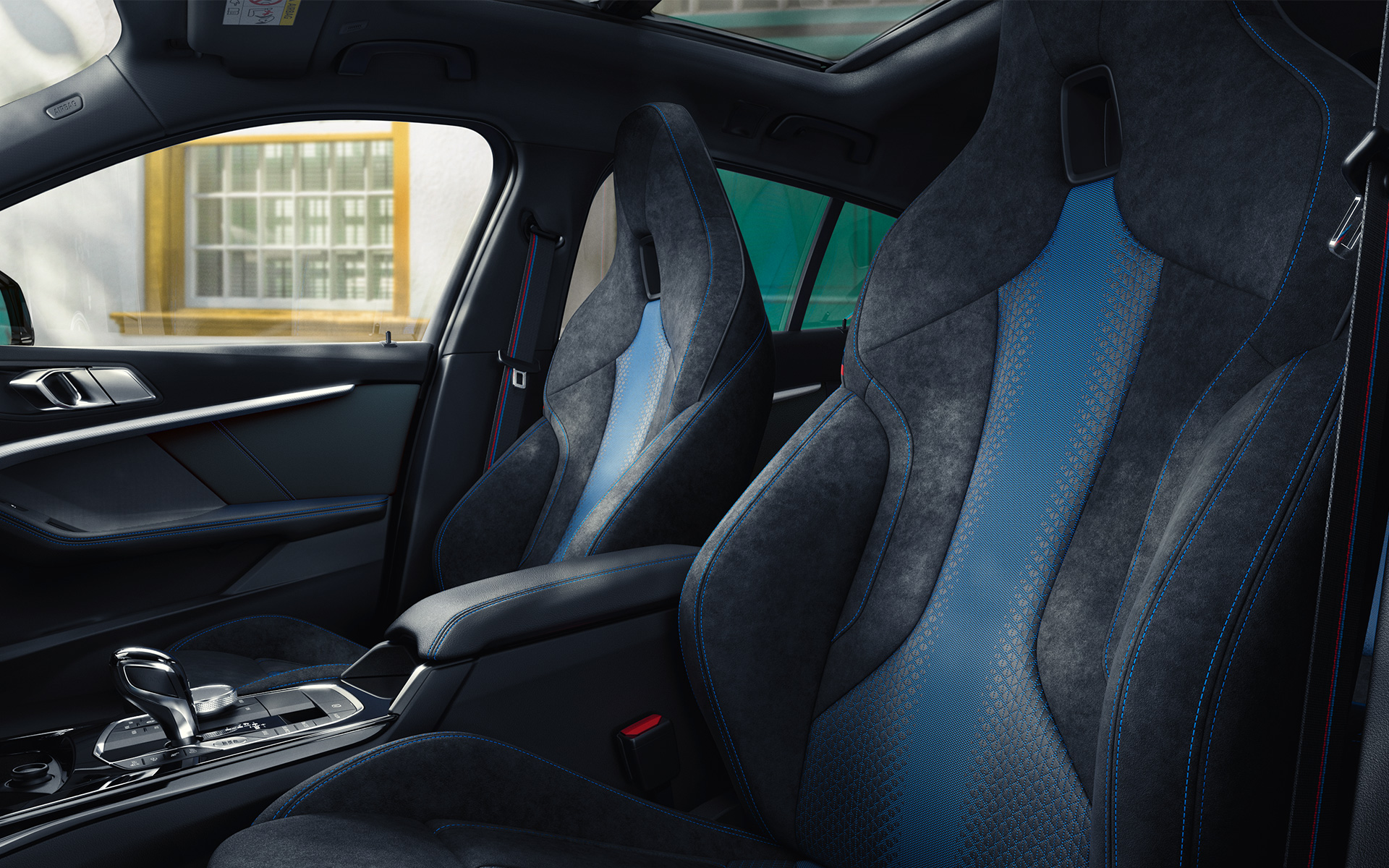 Sièges M sport au galbe ergonomique de la BMW Série 1 F40, avec surpiqûres contrastées bleues et appuie-têtes intégrés.