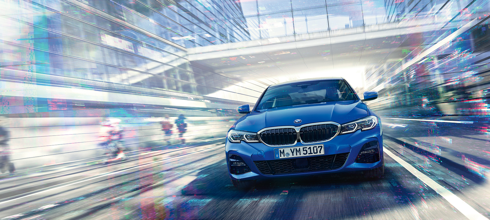 BMW Série 3 Berline, vue de face. Vue de face de la BMW Série 3 Berline en mouvement de jour sous des immeubles de verre.