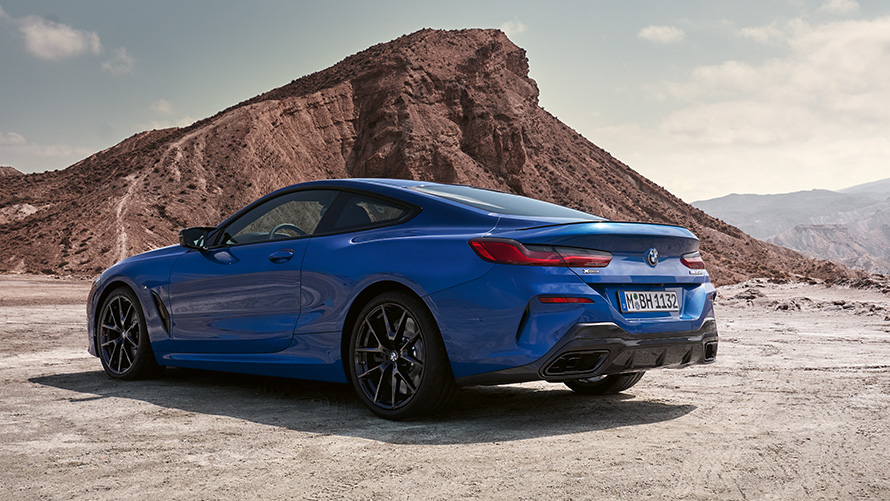 Vue de trois quarts arrière de la nouvelle BMW Série 8 Coupé Pack M Sport G15 LCI restylage 2022 La nouvelle BMW Série 8 Coupé Pack M Sport G15 LCI restylage 2022 M Portimao Blau metallic vue de trois quarts arrière face à des rochers