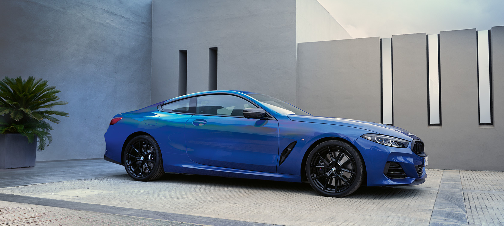 La nouvelle BMW Série 8 Coupé G15 LCI restylage 2022 M Portimao Blau metallic vue de profil en stationnement devant un mur