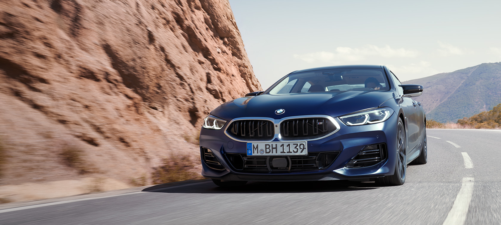 La nouvelle BMW Série 8 Gran Coupé G16 LCI restylage 2022 BMW Individual Frozen Tansanitblau metallic, vue de trois quarts avant, en mouvement sur une route de montagne