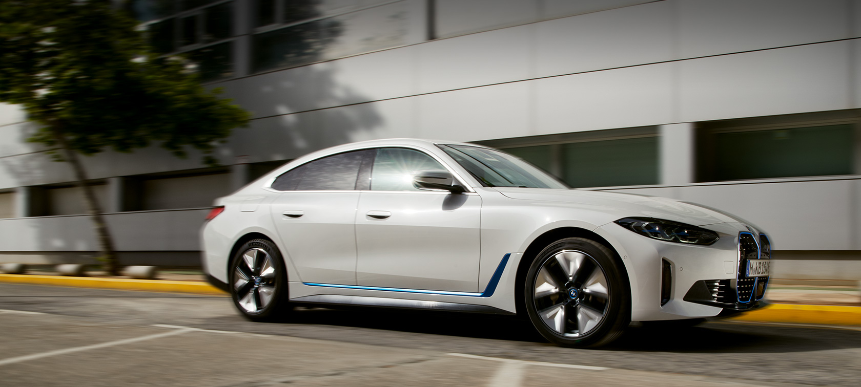 BMW i4 eDrive40 G26 2021 vue de profil de trois quarts en mouvement devant un bâtiment BMW i4 eDrive40 G26 2021 vue de profil de trois quarts en mouvement devant un bâtiment