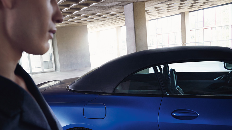 BMW M4 Competition Cabrio avec M xDrive G83 2021 BMW Individual Frozen Portimao Blau metallic avec capote en tissu fermée et homme à l’avant-plan