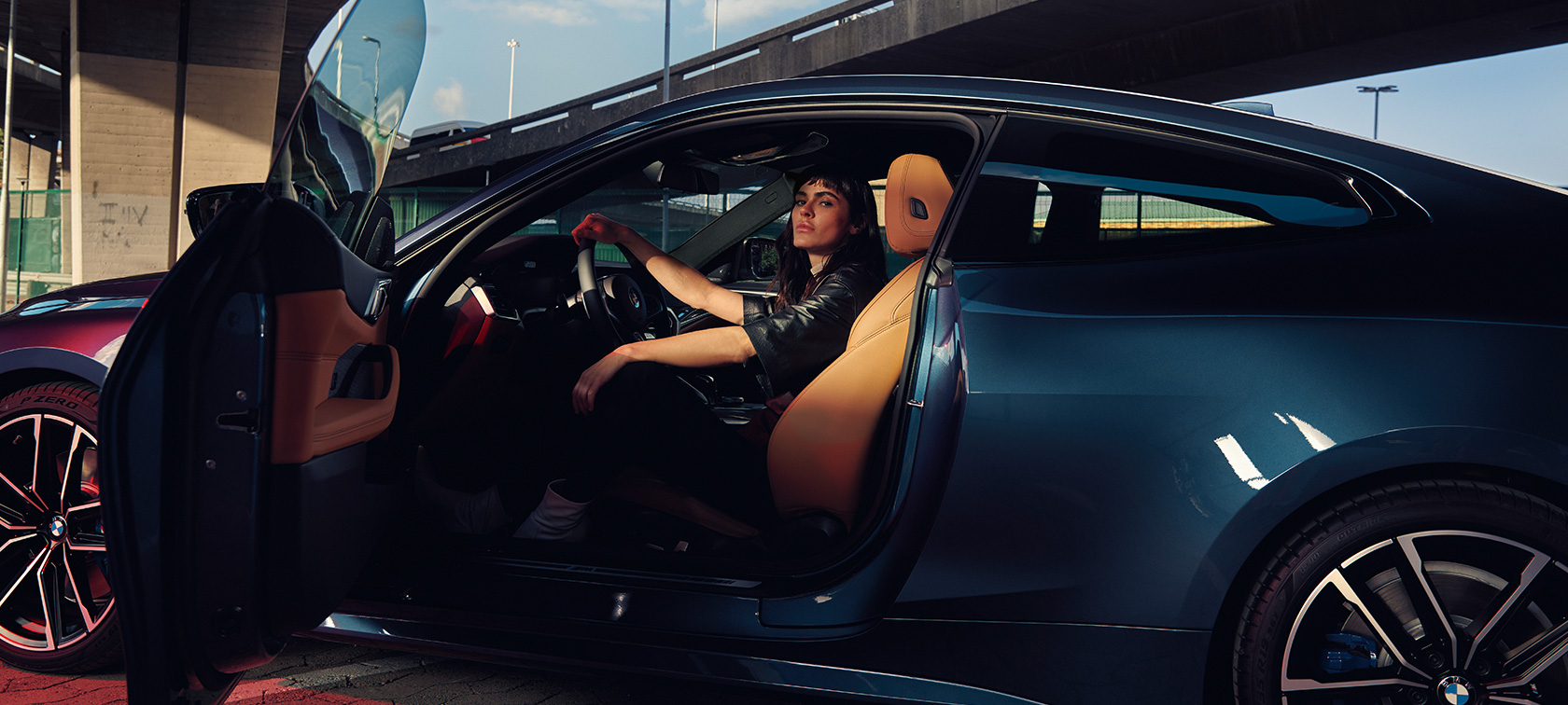 Vue de profil avec modèle BMW M440i xDrive Coupé G22 2020 BMW M440i xDrive Coupé G22 2020 Arctic Race Blue metallic vue de profil modèle assis dans la voiture avec portière ouverte