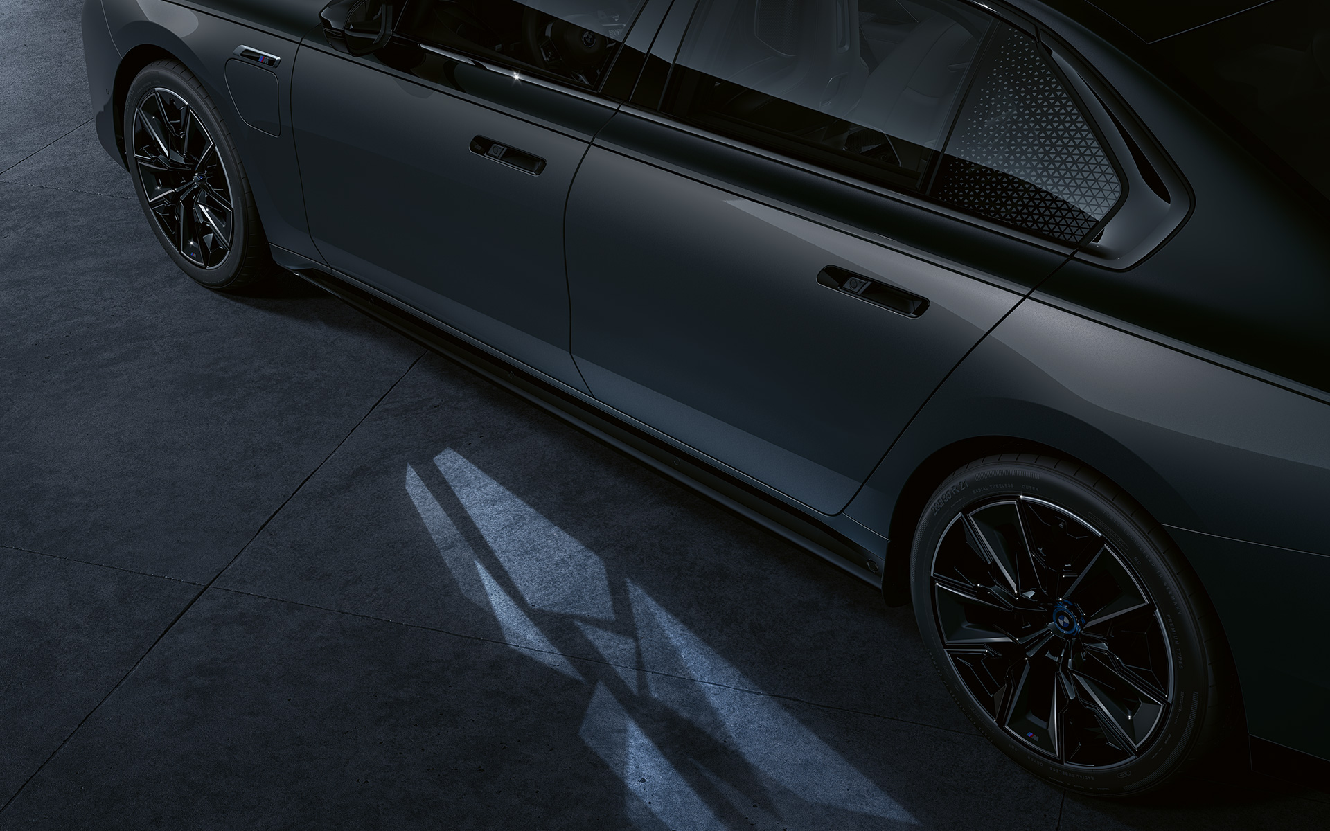 Concept d'éclairage BMW M760e xDrive Berline G70 teinte bi-ton Saphirschwarz metallic BMW Individual Dravitgrau metallic vue en gros plan latérale avec Welcome Light Carpet activé