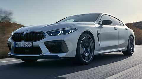 BMW M8 Gran Coupé (F93) vue de trois quarts de profil à l’arrêt avec modèle