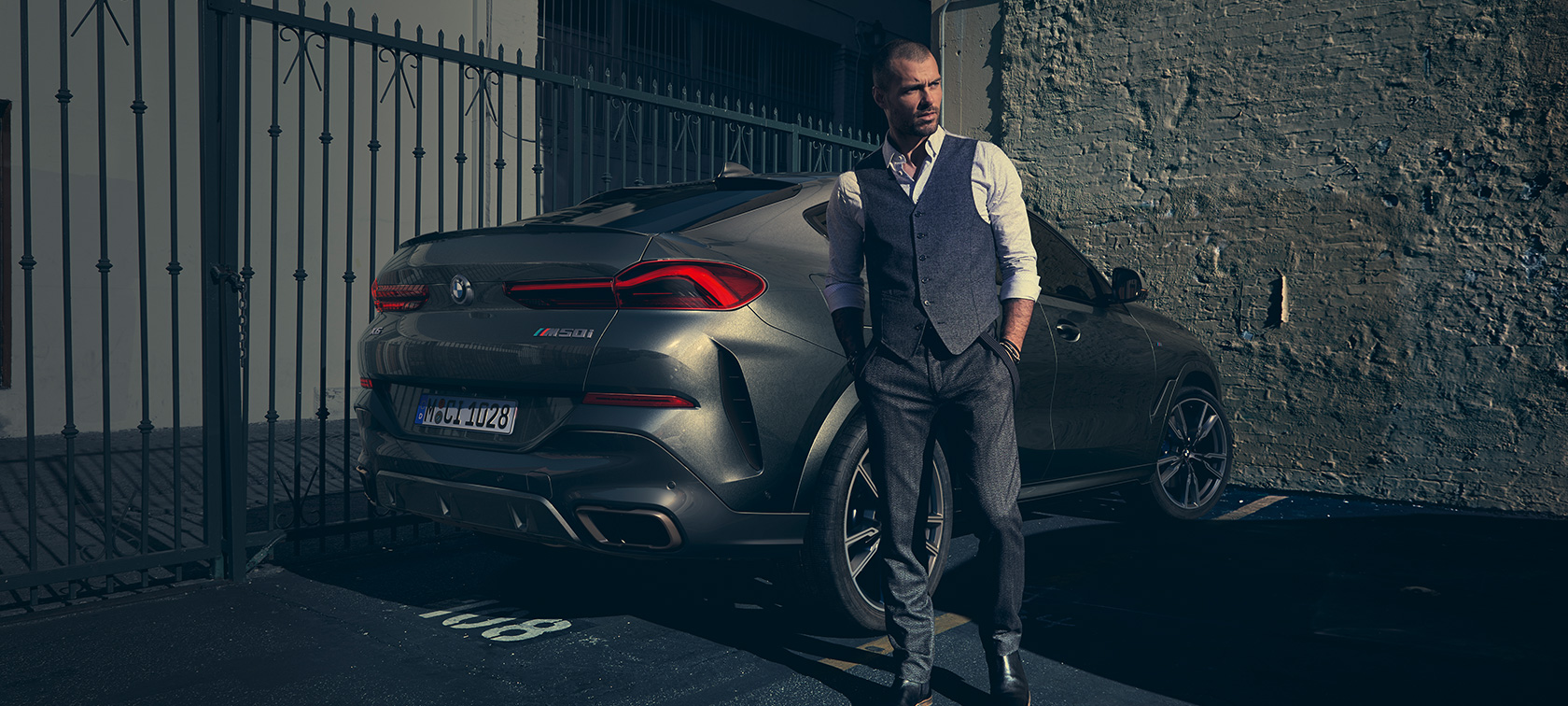 BMW X6 M50i vue de trois quarts arrière G06 Homme debout à côté d’une BMW X6 M50i G06 2018 SUV vue de trois quarts arrière