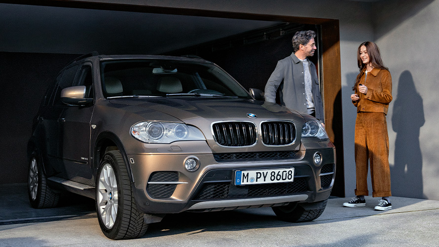 BMW Value Service BMW X2 G05, homme et femme sont debout à côté du véhicule BMW sur une montée de garage